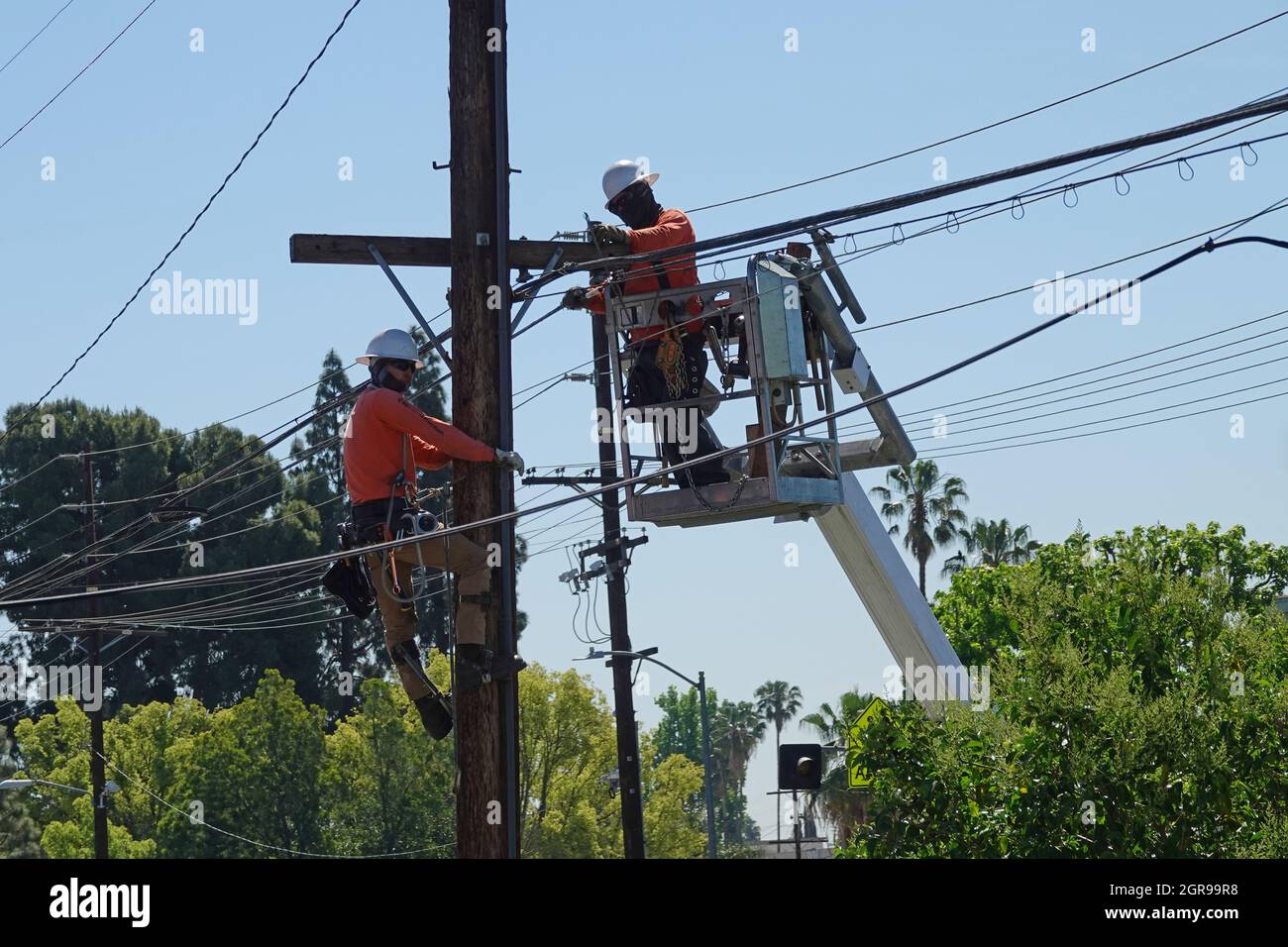 Los Angeles, CA / USA - 29 aprile 2021: I linesmen elettrici sono mostrati aggiornando i cavi di telecomunicazione lungo le linee telefoniche durante il giorno. Foto Stock