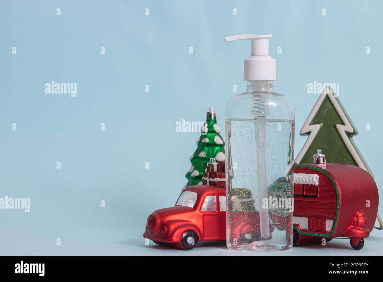 Figurine di Natale e un disinfettante per le mani isolato su sfondo blu Foto Stock