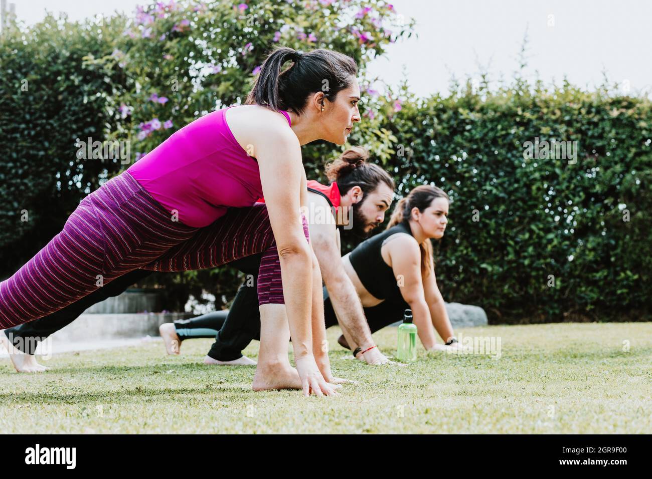 Giovani ispanici che allungano gambe e braccia in una lezione di yoga all'aperto in America Latina Foto Stock