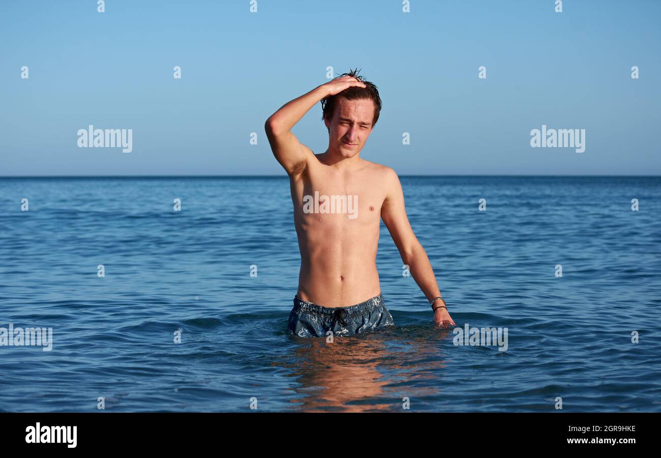 Un maschio spagnolo in piedi in acqua di mare, in posa e divertirsi. Foto Stock
