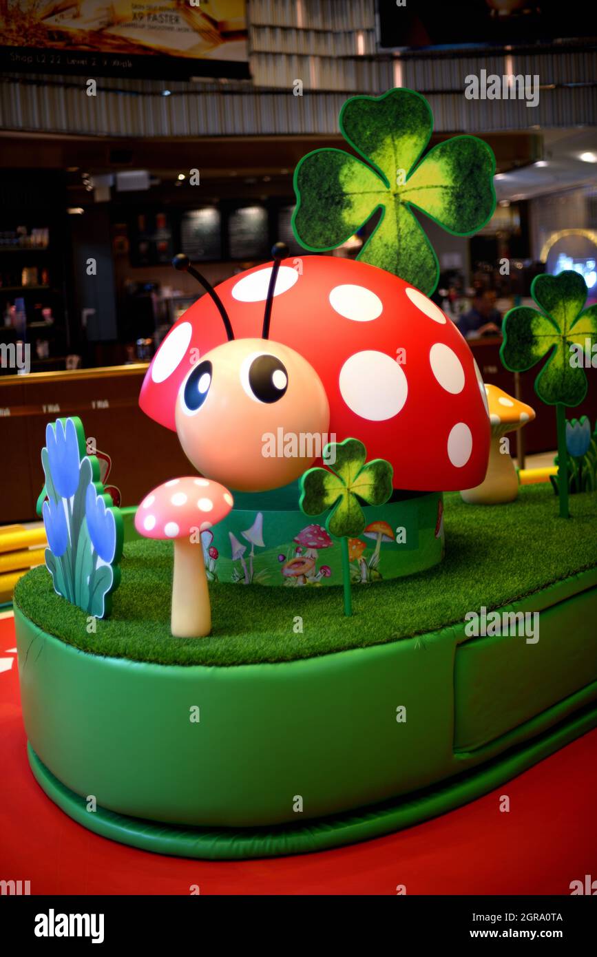 Ladybug, fungo e trifoglio a quattro foglie costituiscono una decorazione di scena giardiniera all'interno di una galleria di negozi, Hong Kong Foto Stock