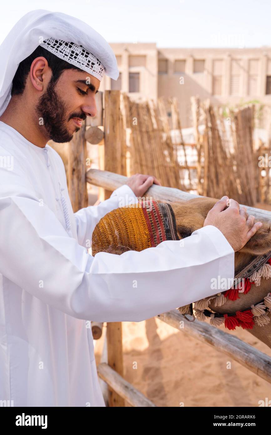 Uomo arabo in abito tradizionale cammello bambino stroking Foto stock -  Alamy
