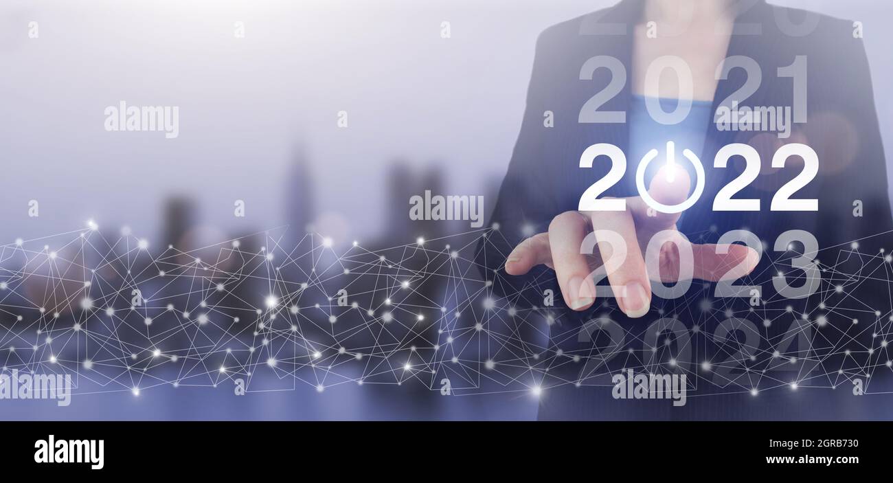 2022 nuove tecnologie intelligenti e nuove tendenze tecnologiche nel 2022. Mano touch schermo digitale ologramma 2022 segno sulla città luce sfondo sfocato. Concept St Foto Stock