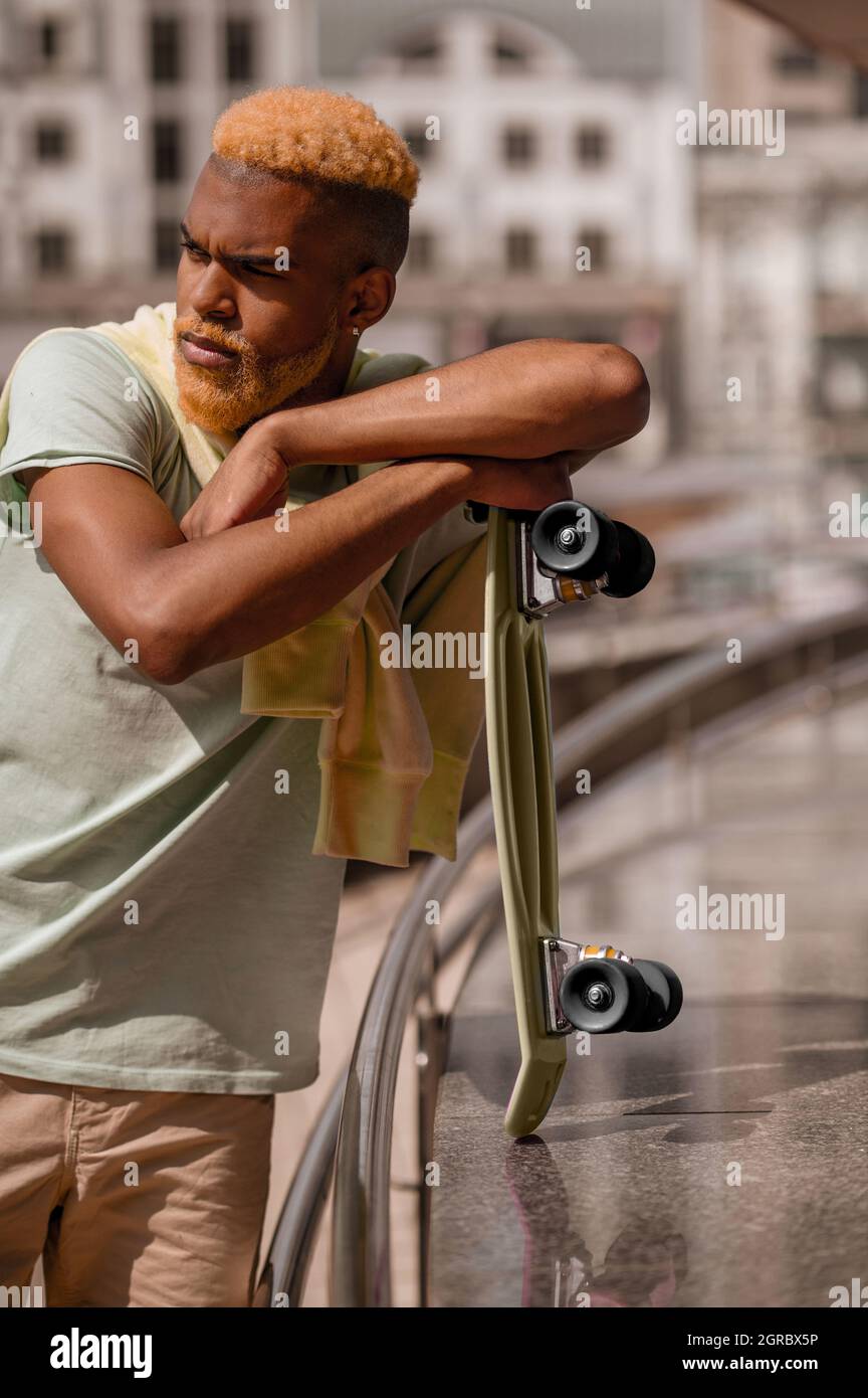 Giovane uomo con pelle scura con skateboard Foto Stock
