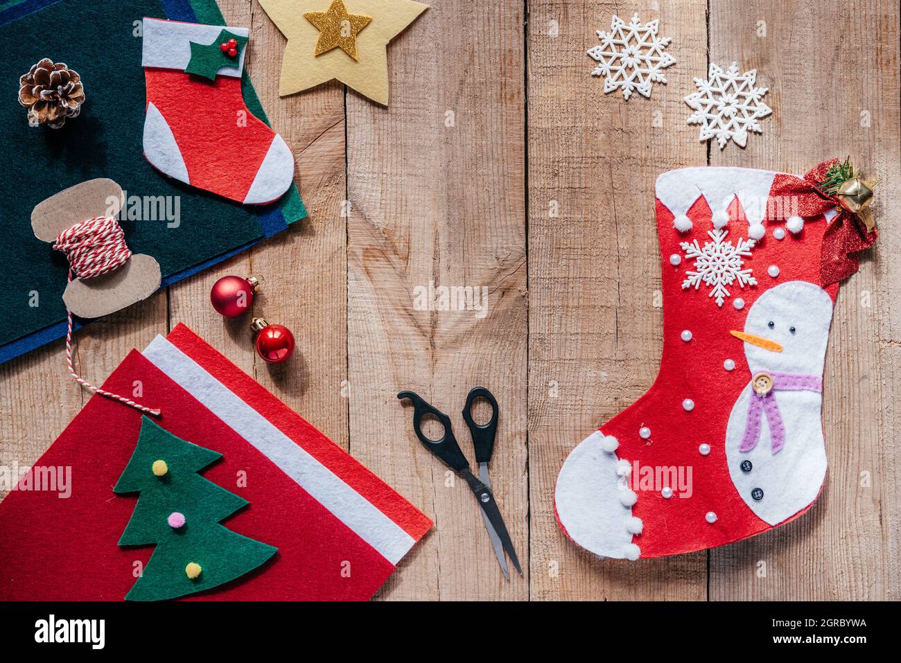 Facendo autocostruire le calze di Natale del feltro, l'artigianato di Natale  e di Capodanno per i bambini, gli ornamenti dell'albero di Natale del feltro,  il filetto e le forbici sul backgrou di