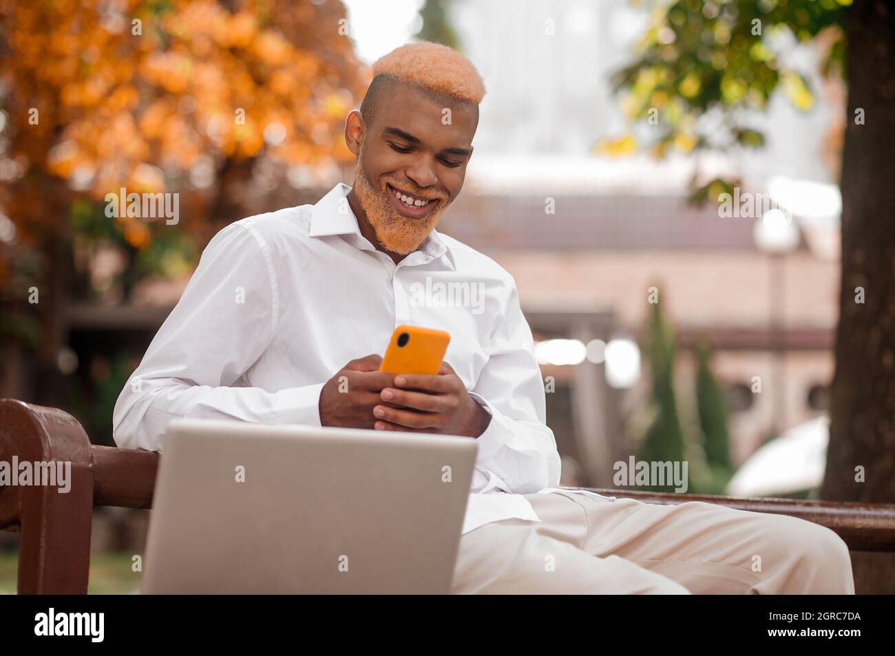 Un uomo elegante dall'aspetto positivo con uno smartphone Foto Stock