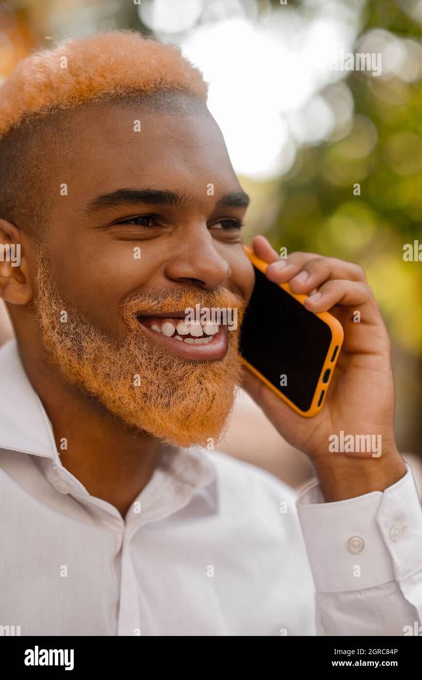 Un uomo elegante dall'aspetto positivo con uno smartphone Foto Stock