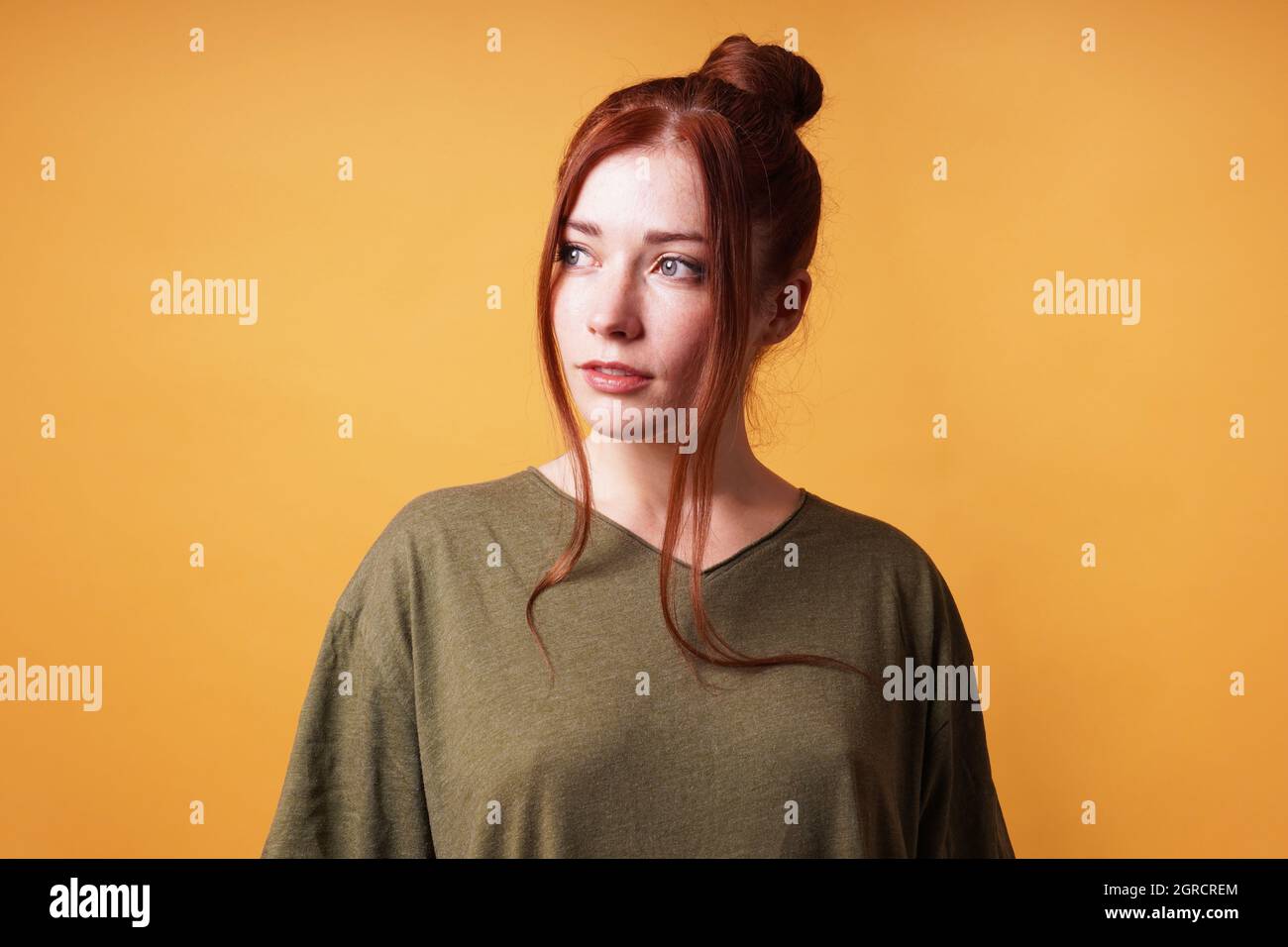 ritratto di bella giovane donna con capelli rossi bun guardare via Foto Stock