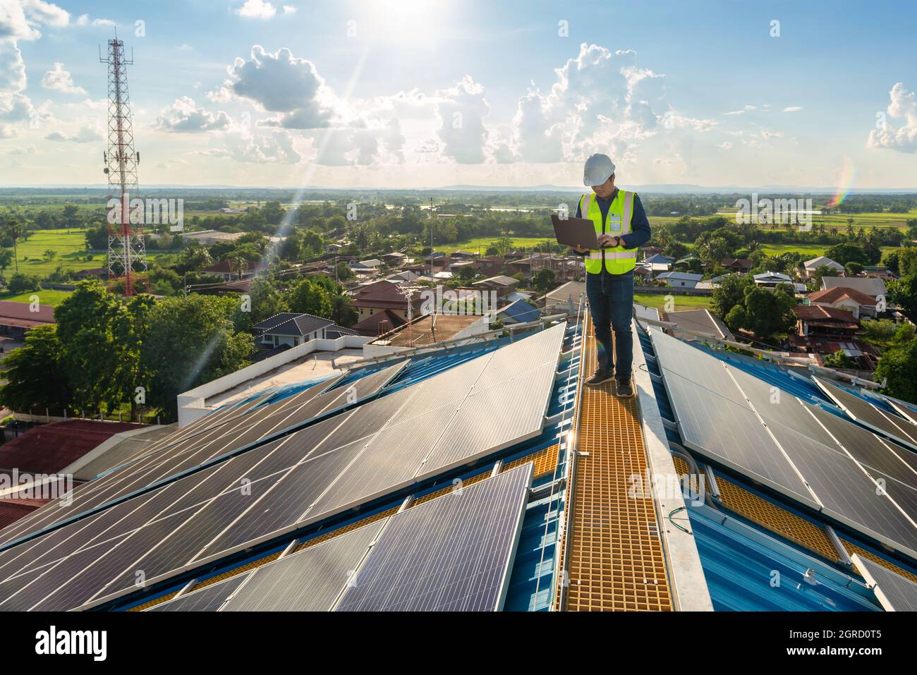 Un ingegnere dell'energia solare che utilizza un computer portatile per controllare la centrale elettrica, manutenzione del tetto solare, energia solare. Foto Stock