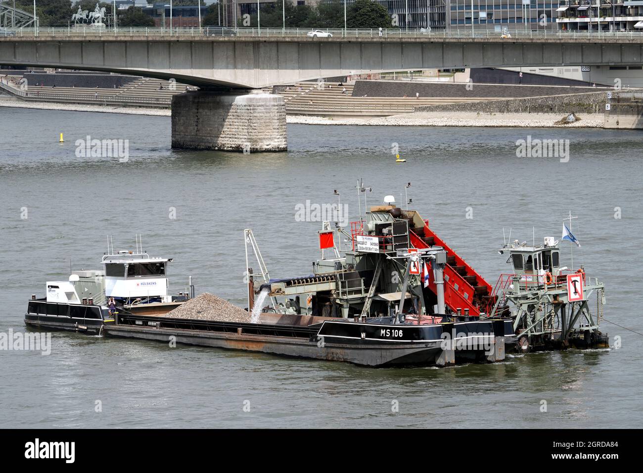 Un drago della società Hülskens Wasserbau approfondisce e allarga il canale di navigazione nel fiume Reno vicino a Colonia. ---- Baggerschiff der Firma Hülskens Hydrotechnik vertieft und verbreitert im Rhein in Köln die Fahrrinne für die Schiffahrt. Foto Stock