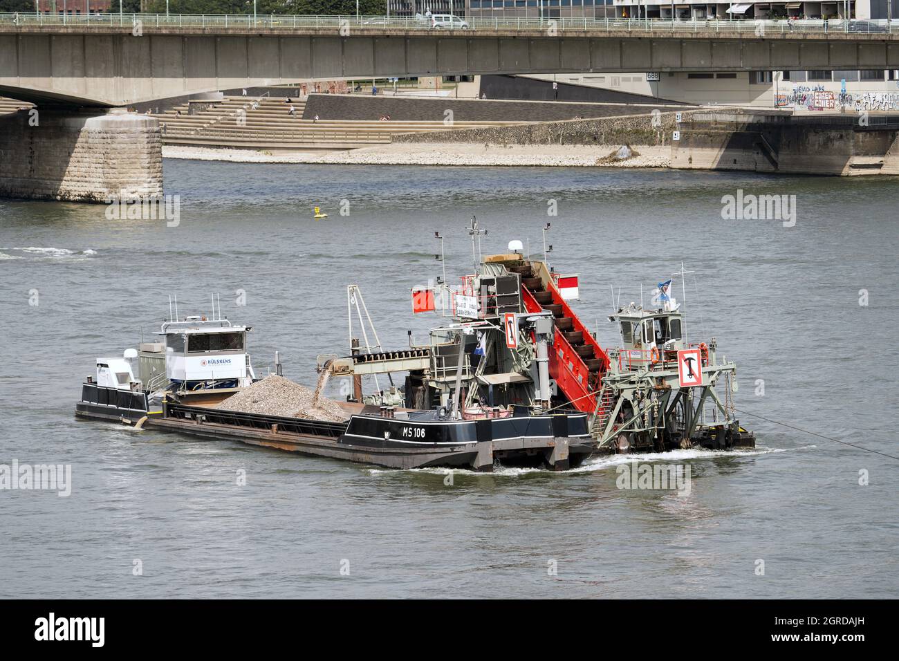 Un drago della società Hülskens Wasserbau approfondisce e allarga il canale di navigazione nel fiume Reno vicino a Colonia. ---- Baggerschiff der Firma Hülskens Hydrotechnik vertieft und verbreitert im Rhein in Köln die Fahrrinne für die Schiffahrt. Foto Stock