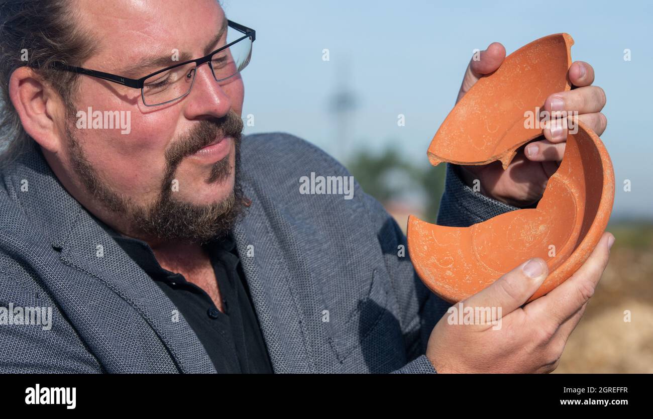 Deiningen, Germania. 01 ottobre 2021. L'archeologo Manfred Woidlich contiene una ciotola di ceramica rotta con incisioni. Durante gli scavi nella Nördlinger Ries, gli archeologi hanno trovato questa ciotola, che proviene dall'Africa, tra gli altri beni sepolti in una tomba del VI secolo. Credit: Stefan Puchner/dpa/Alamy Live News Foto Stock