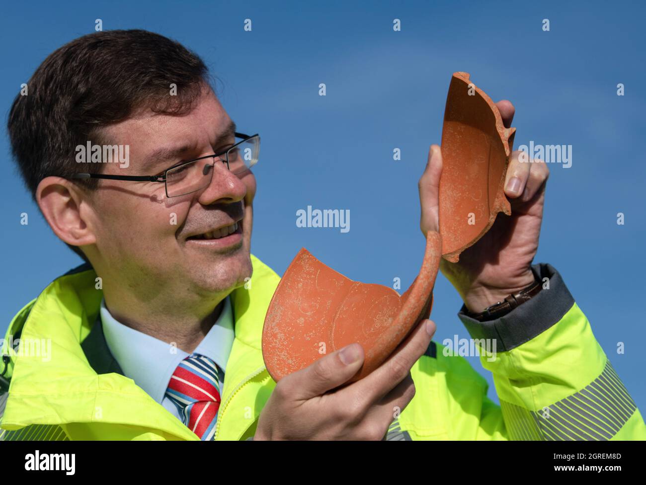 Deiningen, Germania. 01 ottobre 2021. Johann Friedrich Tolksdorf, direttore dell'area dell'Ufficio di Stato bavarese per la conservazione dei monumenti, ospita una ciotola in ceramica con incisioni. Durante gli scavi nella Nördlinger Ries, gli archeologi hanno trovato questa ciotola, che proviene dall'Africa, tra gli altri beni sepolti in una tomba del VI secolo. Credit: Stefan Puchner/dpa/Alamy Live News Foto Stock