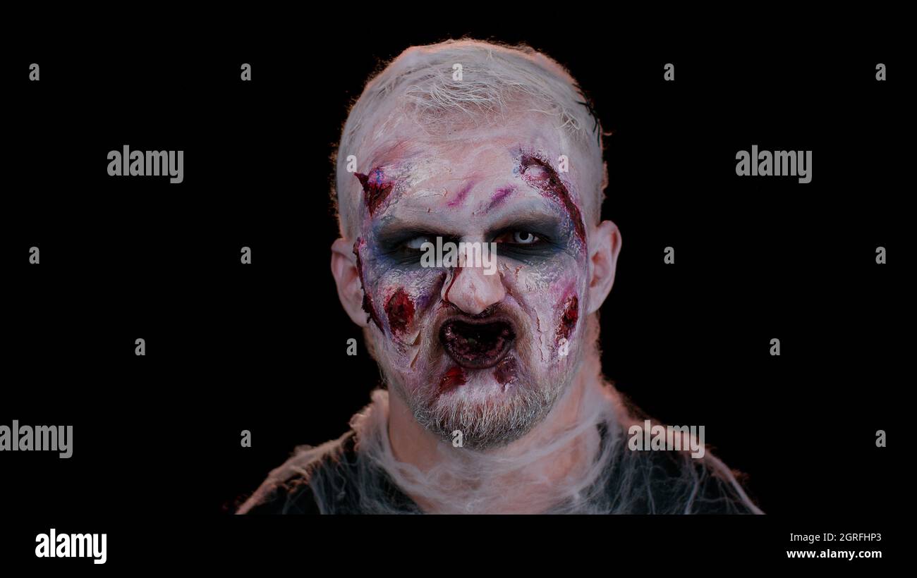 Uomo sinistro con orribile spaventoso Halloween zombie trucco in  convulsioni facendo volti cercando di spaventare Foto stock - Alamy