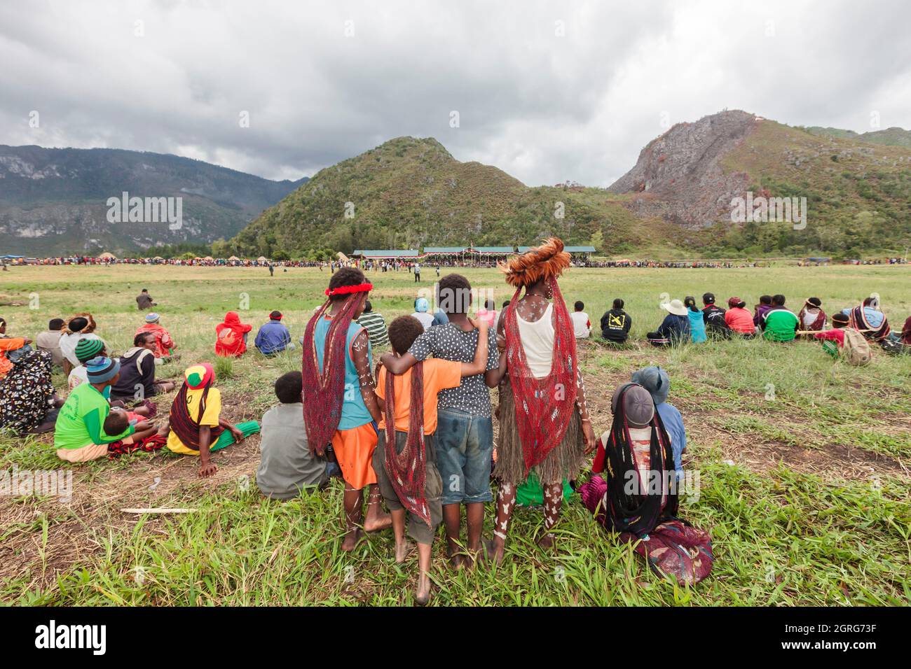 Indonesia, Papua, la città di Wamena, i bambini Dani guardano al sito del festival culturale, di fronte agli stand. Baliem Valley Cultural Festival, ogni agosto, le tribù si riuniscono per eseguire scene di guerra ancestrali, sfilate e danze in abiti tradizionali Foto Stock