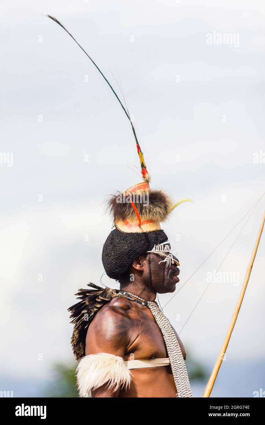 Indonesia, Papua, città di Wamena, ritratto di profilo di un uomo della tribù Dani, con un eredico con una lunghissima piuma d'uccello. Baliem Valley Cultural Festival, ogni agosto, le tribù si riuniscono per eseguire scene di guerra ancestrali, sfilate e danze in abiti tradizionali Foto Stock