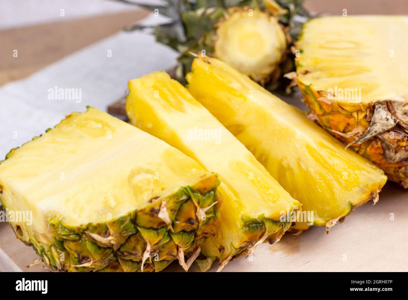 Fette di frutta fresca e succosa di ananas giallo su sfondo di legno chiaro. Foto Stock
