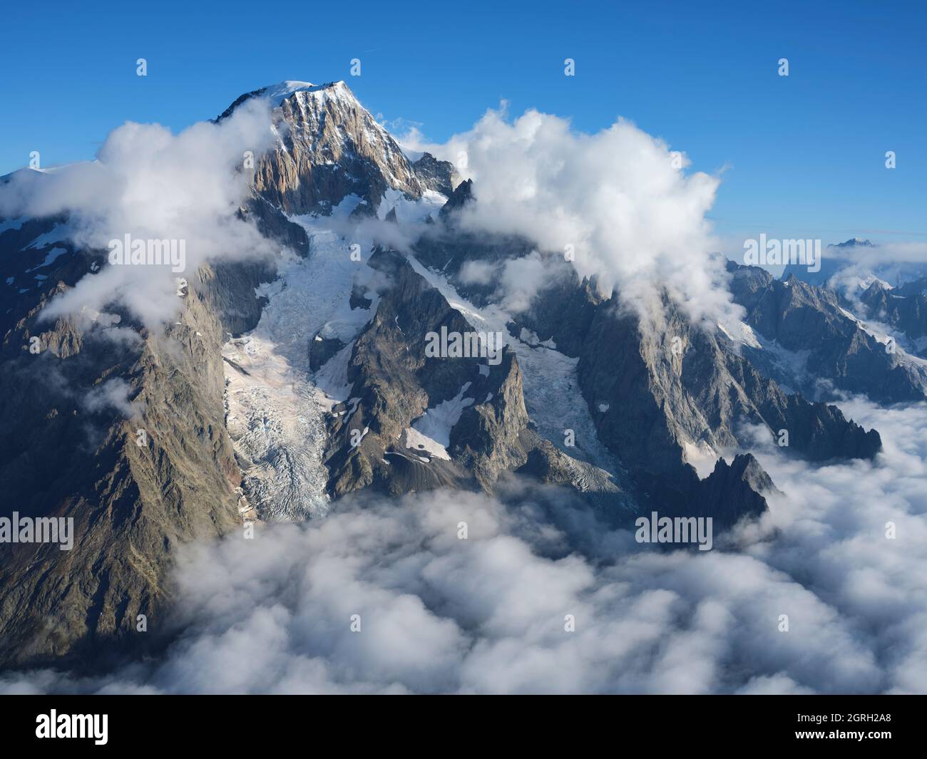 VISTA AEREA. Faccia orientale del Monte Bianco nella luce del mattino sopra alcune nuvole basse. Courmayeur, Valle d'Aosta, Italia. Foto Stock