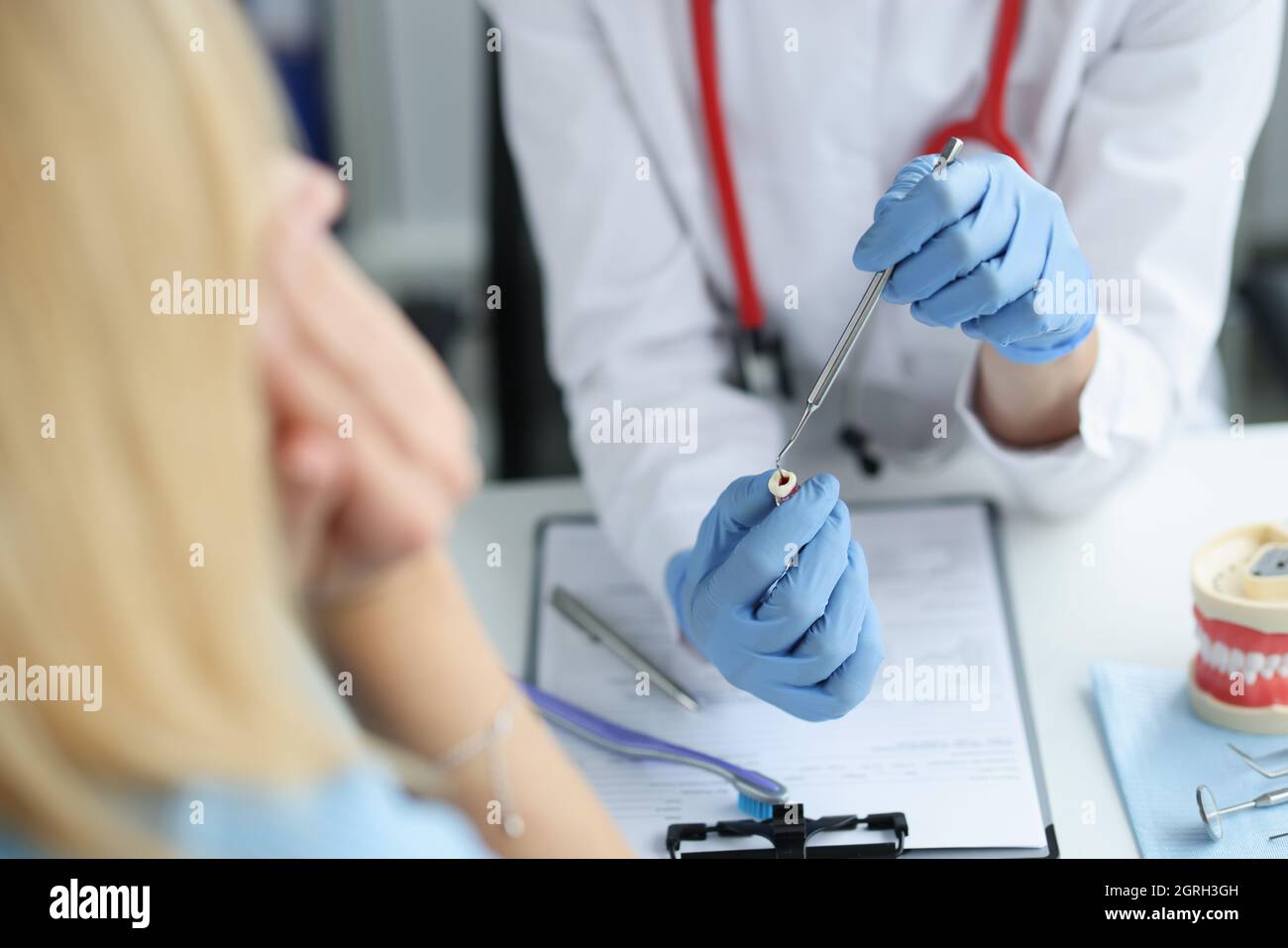 Medico dentista mostra paziente con dentifricio dente con buco interno e carie Foto Stock