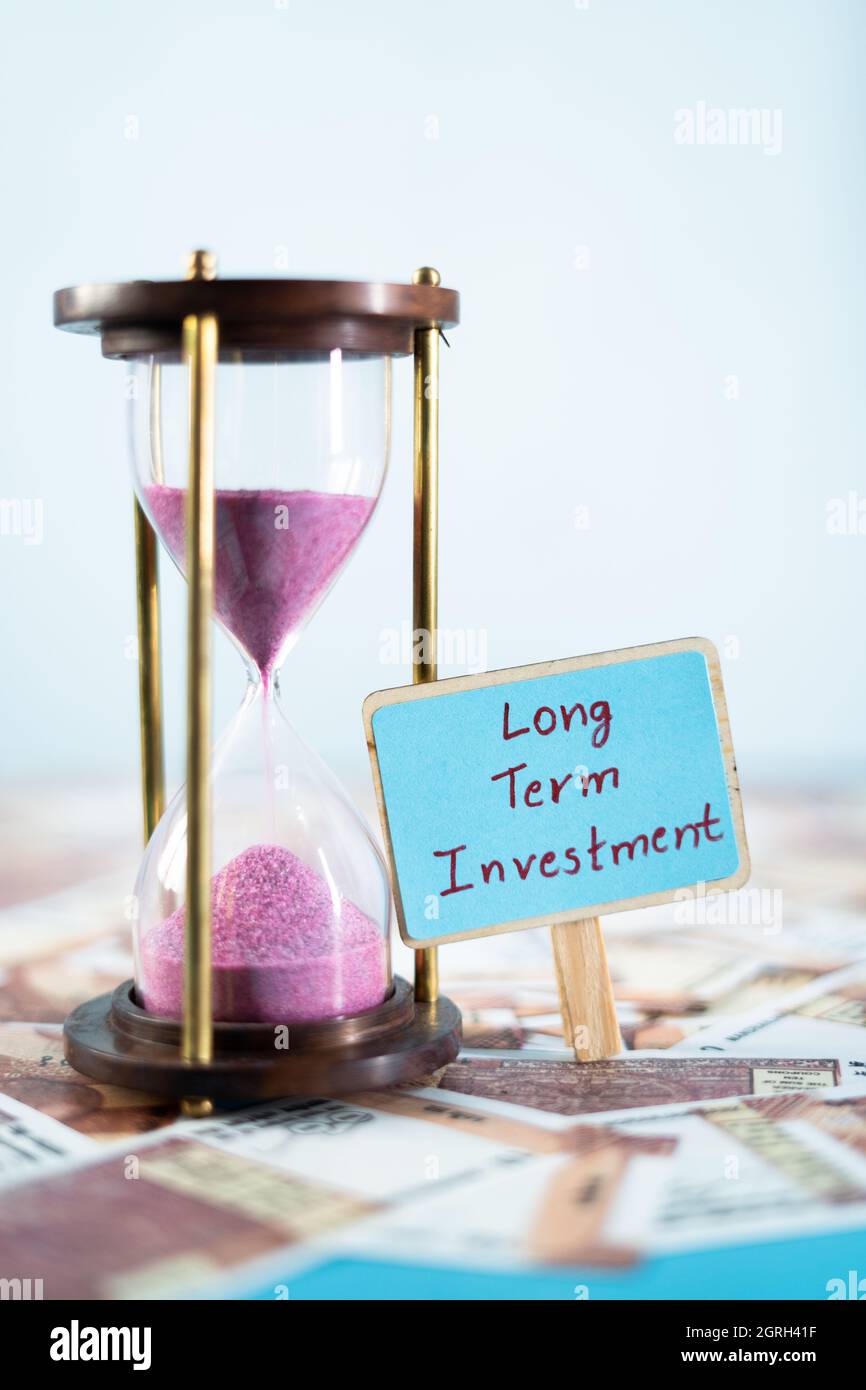 Timer sabbia con cartello di investimento a lungo termine sulle banconote - concetto di piani finanziari e pensionistici futuri. Foto Stock