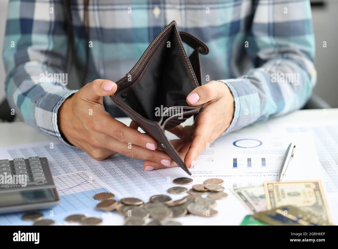 La donna mostra un portafoglio vuoto sulle monete e sui documenti da tavola Foto Stock