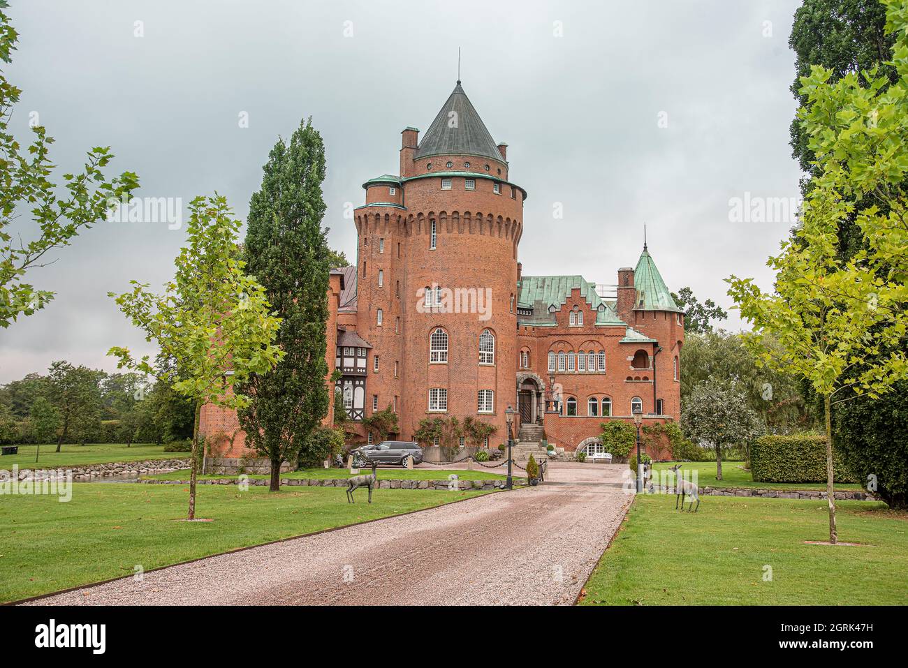 Le alte torri del castello fiabesco Hjularod è un castello rosso romantick all'interno di un parco su un prato verde, Esrov, Svezia, 16 settembre 2021 Foto Stock