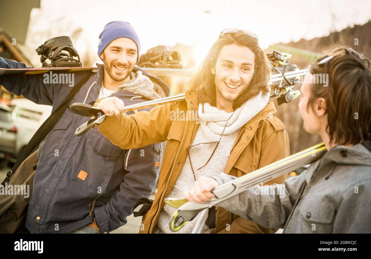 I migliori amici che si divertono insieme camminando con sci e snowboard durante il viaggio in montagna - concetto di amicizia con i giovani ritrovano amanti degli sport invernali Foto Stock