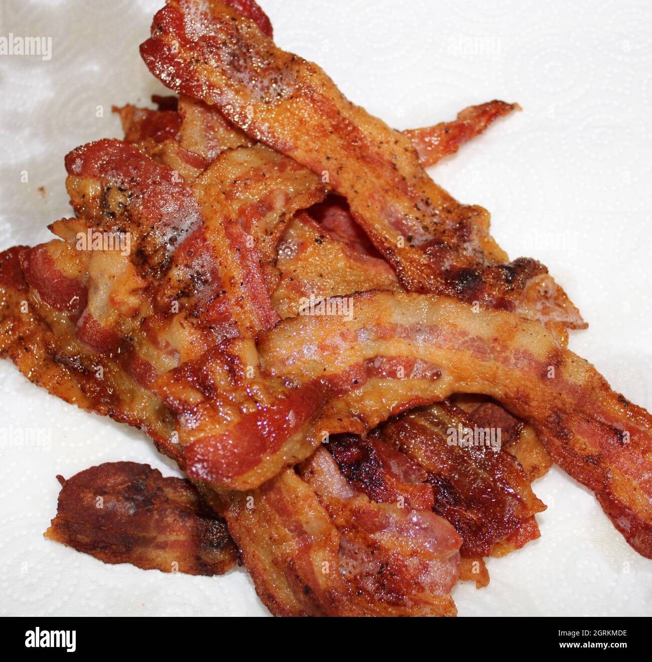 Strisce di pancetta ben cotta impilate l'una sull'altra. Foto Stock