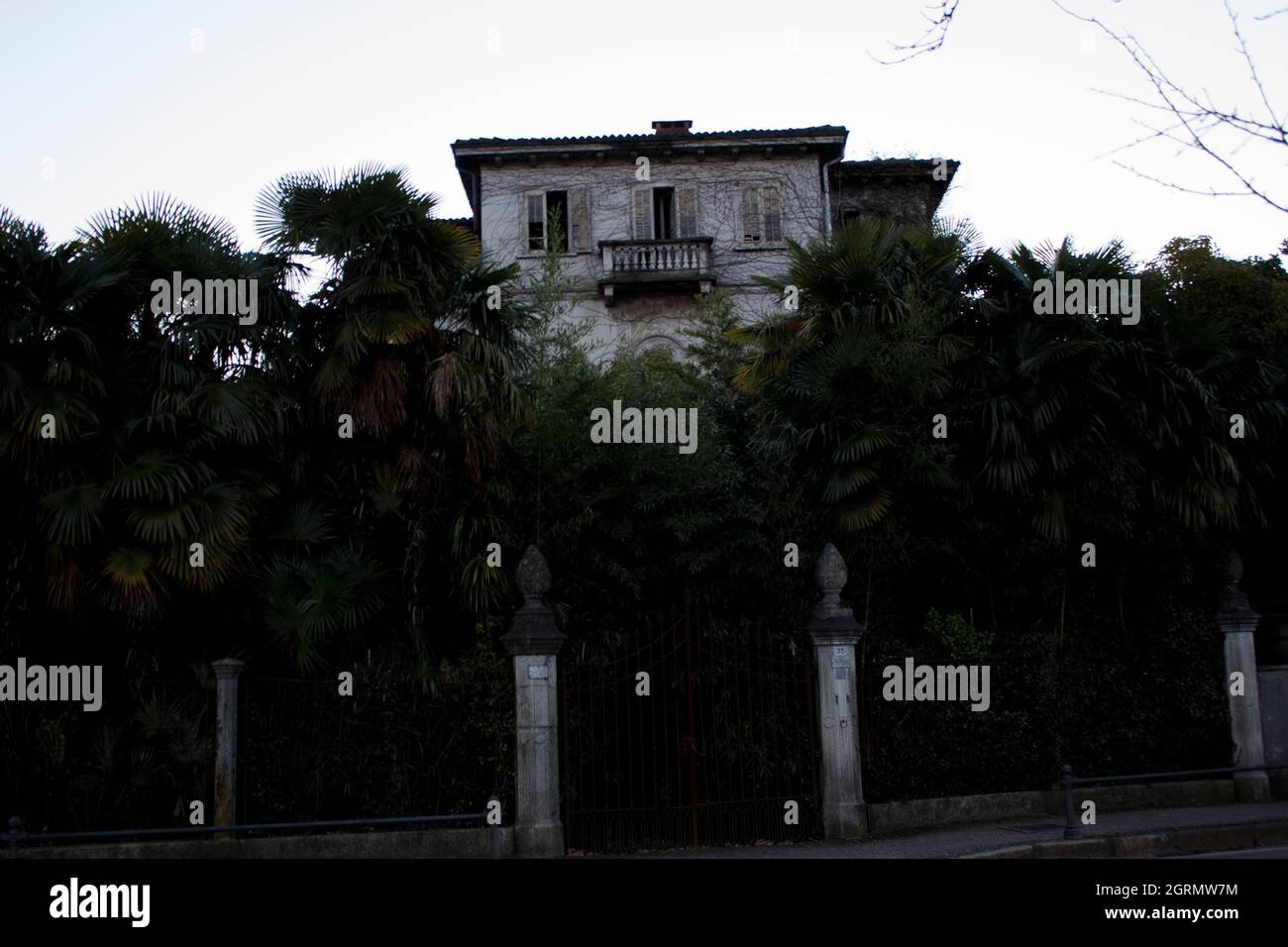 Vecchia villa in rovina, immersa nella vegetazione, nelle tonalità scure tipiche di Halloween, foto deliberatamente sottoesposta per dare un effetto più scuro Foto Stock