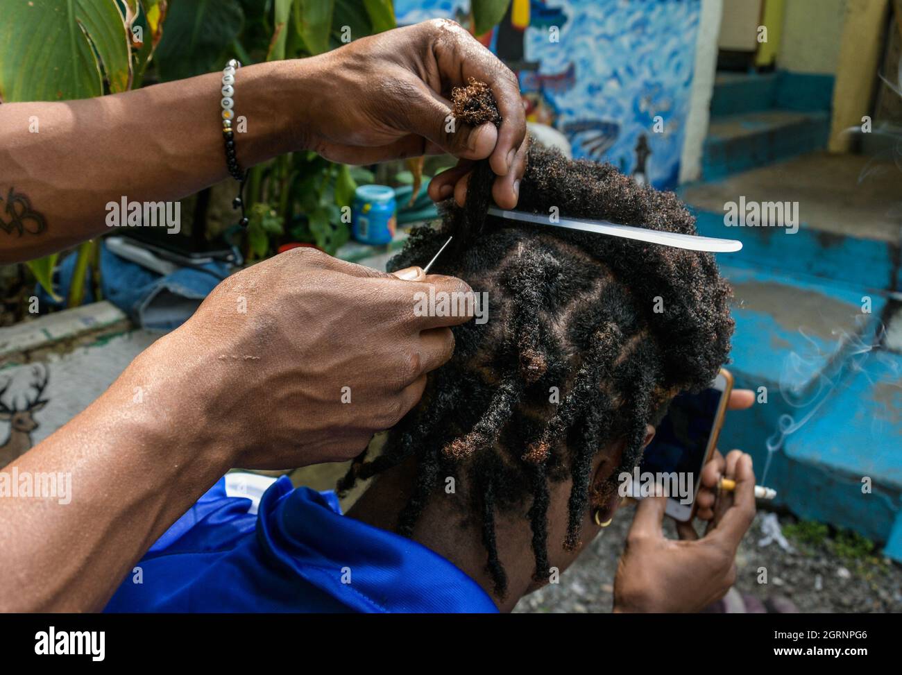 Non esclusiva: CITTÀ DEL MESSICO, MESSICO - 29 SETTEMBRE 2021: Un migrante haitiano è aiutato da un altro migrante a fare le trecce nei suoi capelli durante il loro soggiorno Foto Stock