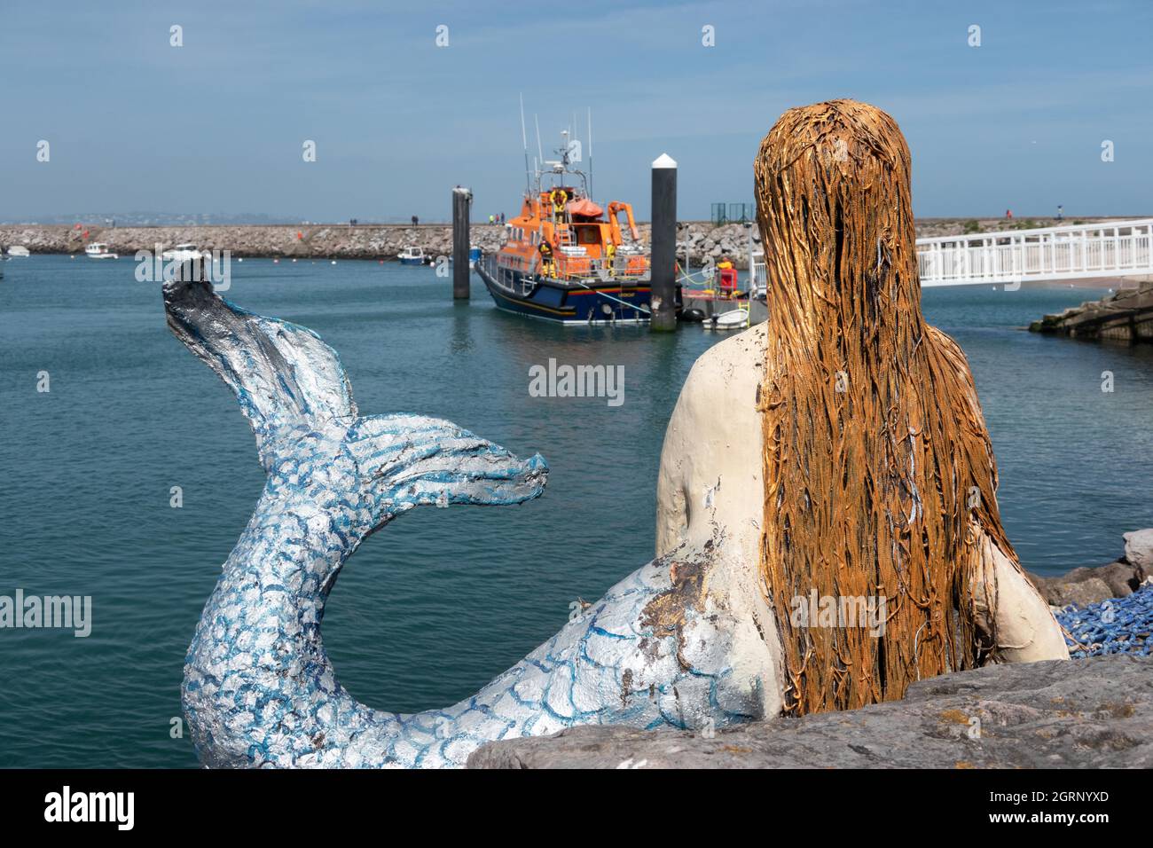 Mermaid guardando verso la scialuppa di salvataggio ormeggiata nel porto di Brixham nel Devon del sud dell'Inghilterra Foto Stock