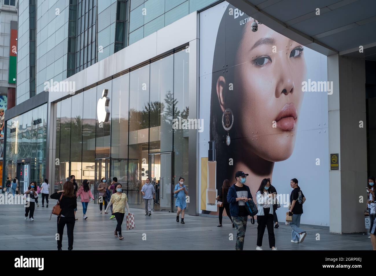 I consumatori cinesi camminano oltre l'etichetta di moda britannica Burberry ad vicino ad un negozio Apple a Pechino, Cina.01-Ott-2021 Foto Stock