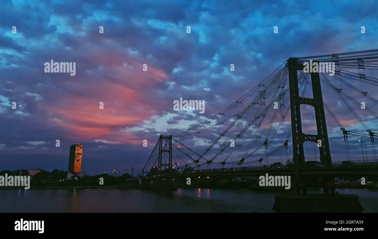 Silhouette del ponte sospeso Sante Fe in Argentina contro un cielo nuvoloso blu e rosa Foto Stock