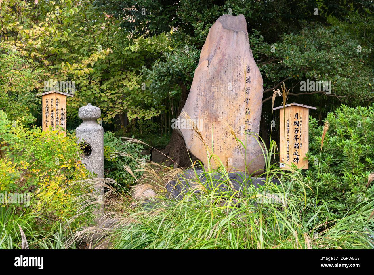 tokyo, giappone - novembre 13 2020: Poema di morte su una stele in pietra giapponese dedicata a Tsukioka Yoshitoshi, tipografo di Ukiyo-e, e una replica di un pilastro di Foto Stock