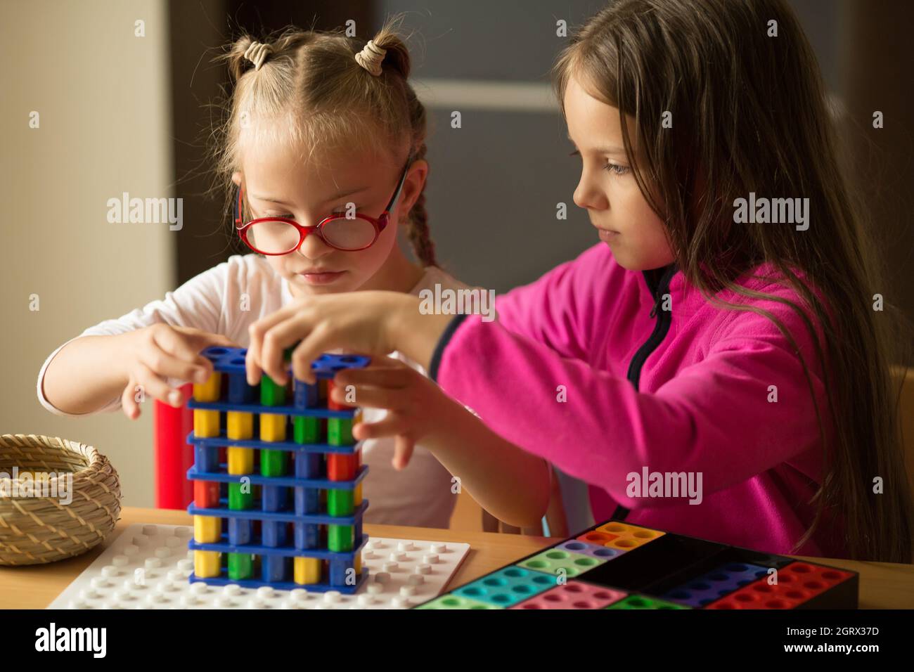 Una ragazza con sindrome di Down gioca un gioco da tavolo con la sorella e impara a contare con l'aiuto di Numicon Foto Stock