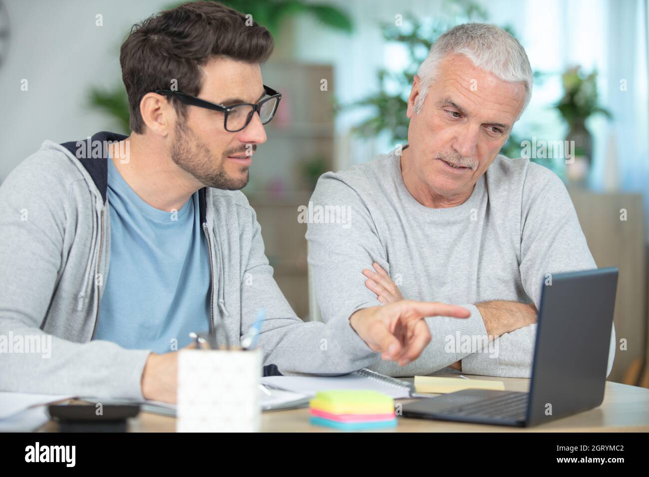 sorridendo padre e figlio con un computer portatile mentre si siede alla scrivania Foto Stock