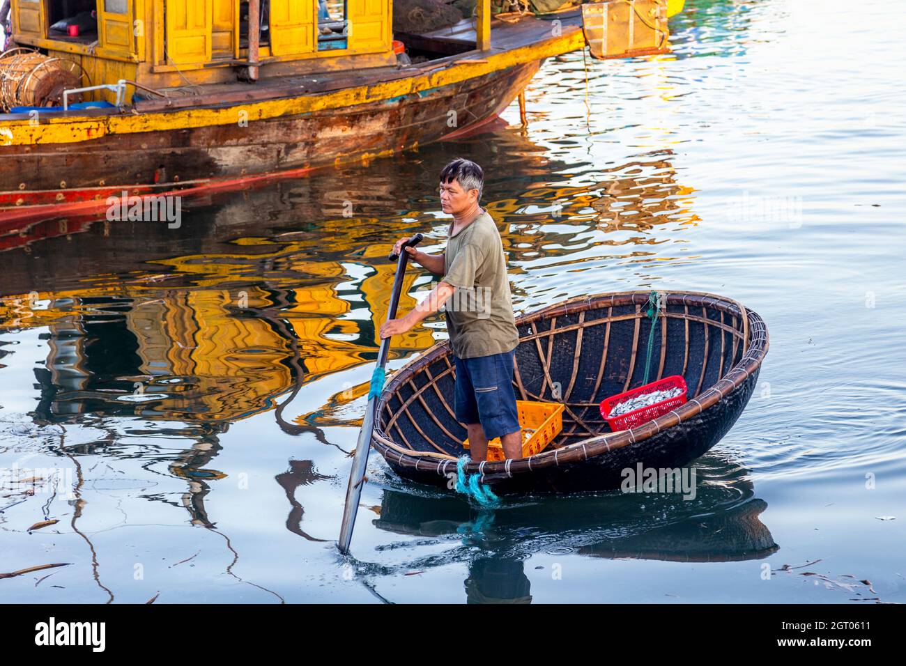 Giro in barca a cestino con uomo vietnamita che si trasporta dalla sua barca da pesca. Foto Stock