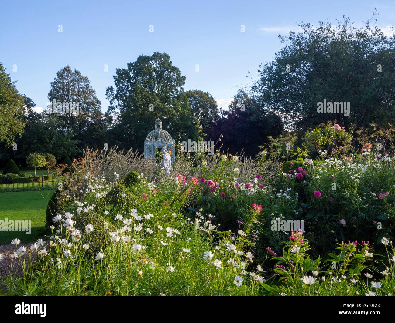 Chenies Manor Parterre e bianco Birdcage pagoda incorniciata dalla fine estate piante Borders.White Marguerittes, dahlias rosa con fine weathe cielo blu. Foto Stock