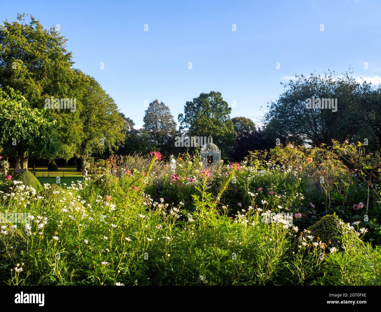Chenies Manor Parterre e bianco Birdcage pagoda incorniciata dalla fine estate piante Borders.White Marguerittes, dahlias rosa con fine weathe cielo blu. Foto Stock