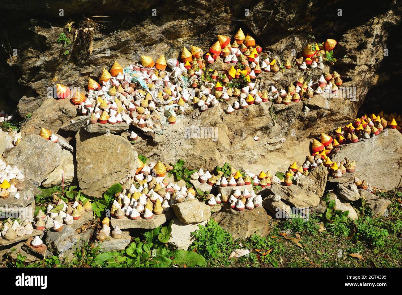 Stupa in miniatura (tsa-tsa) accatastata su rocce nel soleggiato Bhutan. All'interno di ogni argilla tsa-tsa è un piccolo rotolo di preghiere per un umano preferito - vivente o morto Foto Stock