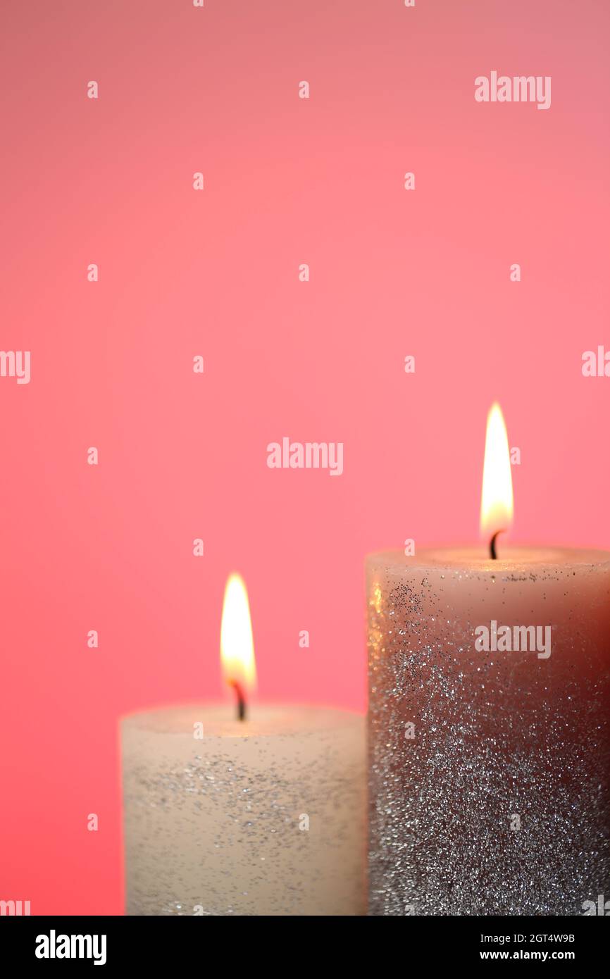 Candela fiamma. Un primo piano luminoso candela su sfondo rosa. Candele Foto Stock