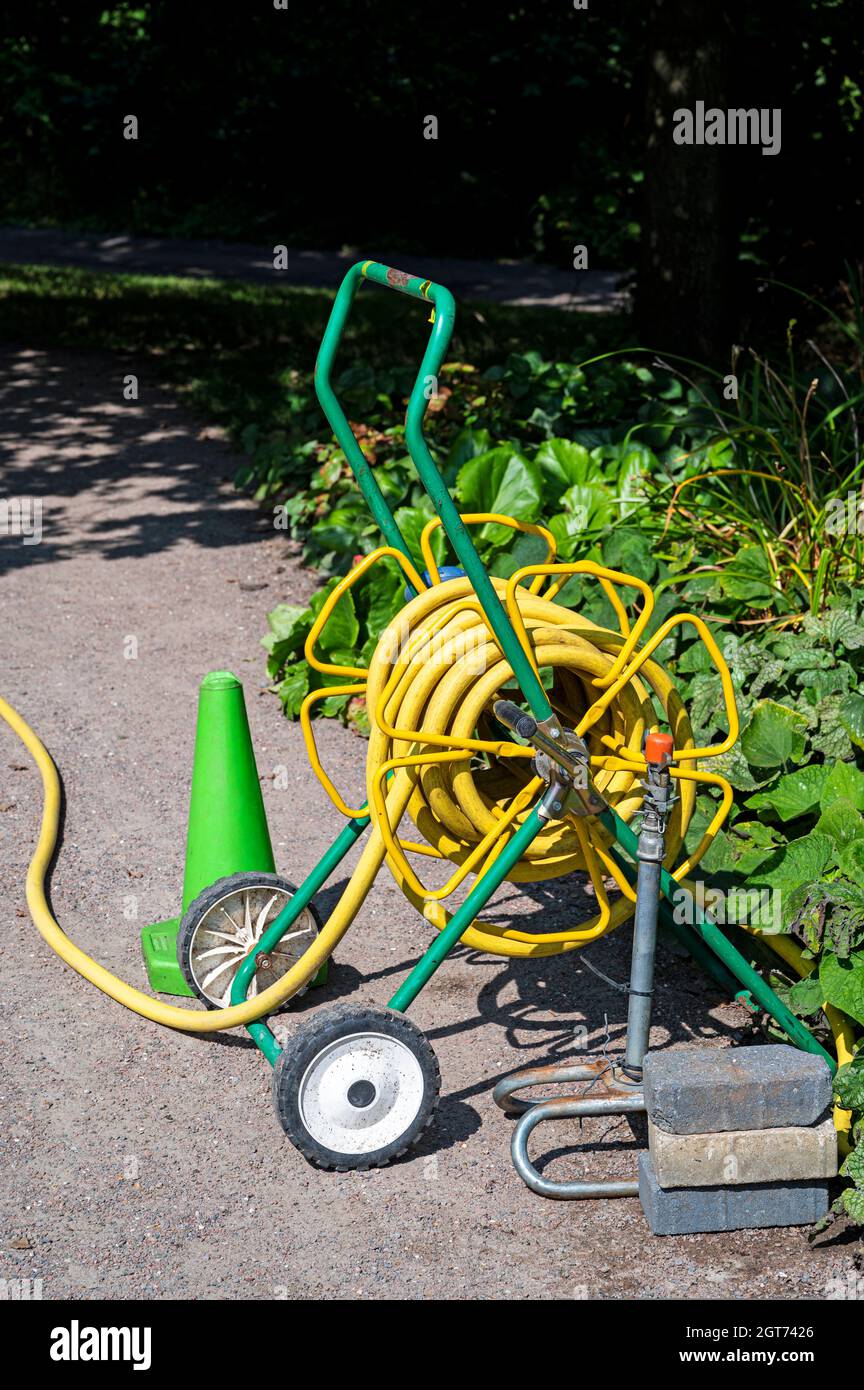 Tubo da giardino giallo su un carrello con ruote. Foto Stock