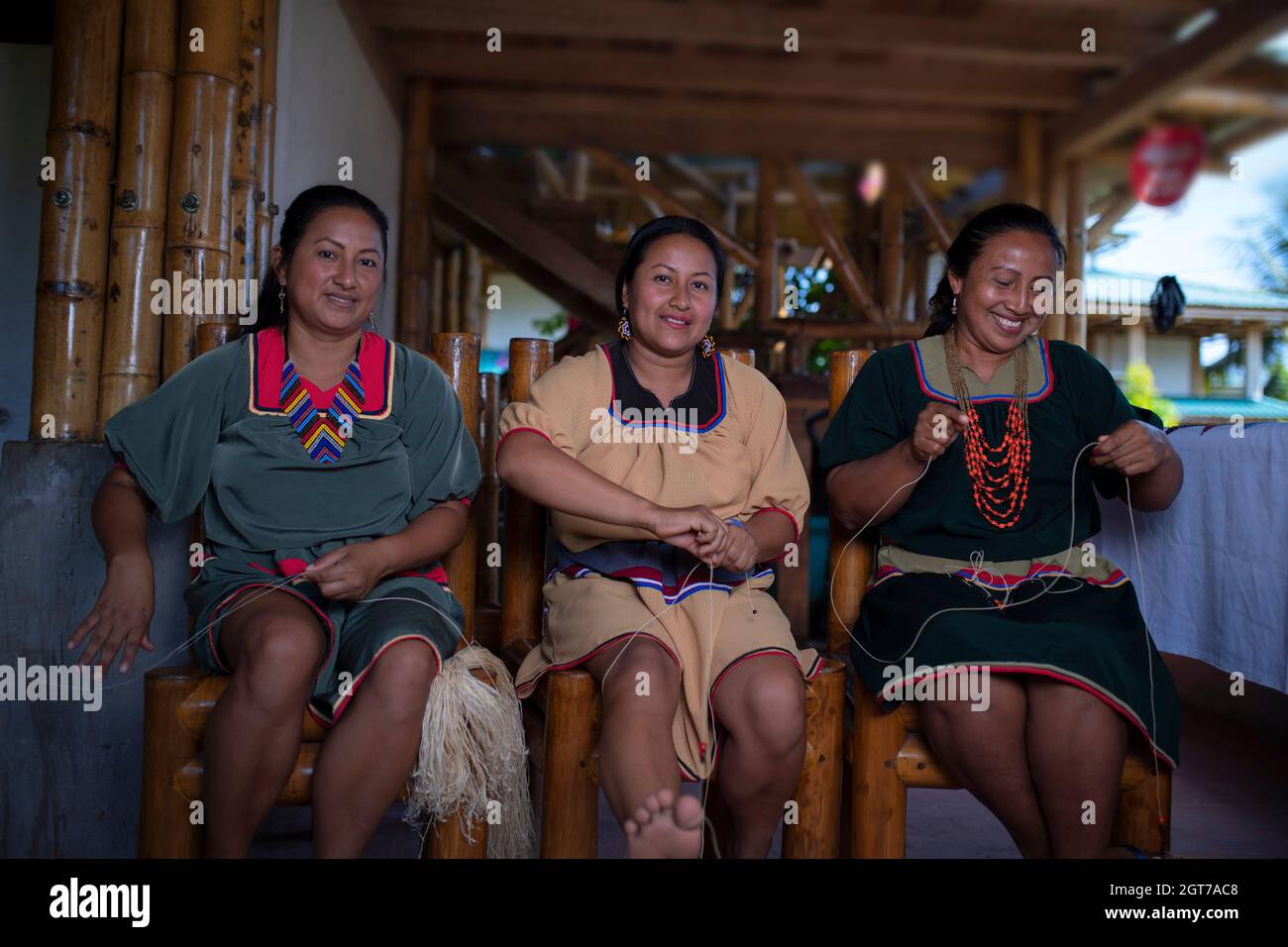 Nueva Loja, Sucumbios / Ecuador - 2 settembre 2020: Donna indigena di nazionalità Cofan con abito verde sorridente mentre tessendo artigianato seduta o Foto Stock