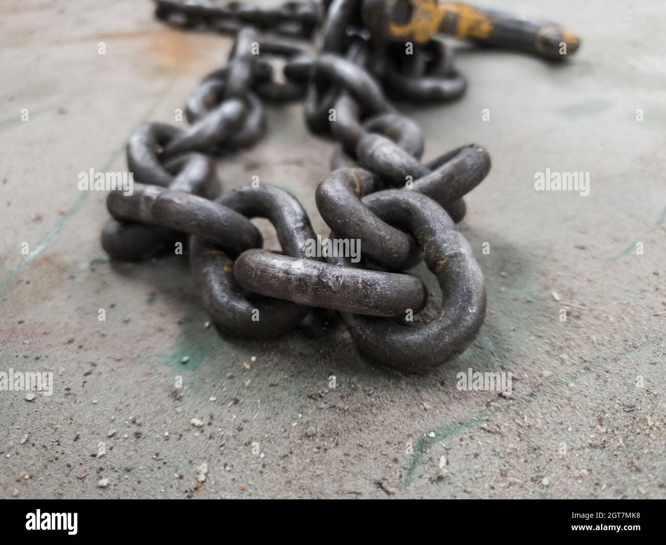 Su di una catena a resistenza industriale su una superficie metallica polverosa. Foto Stock