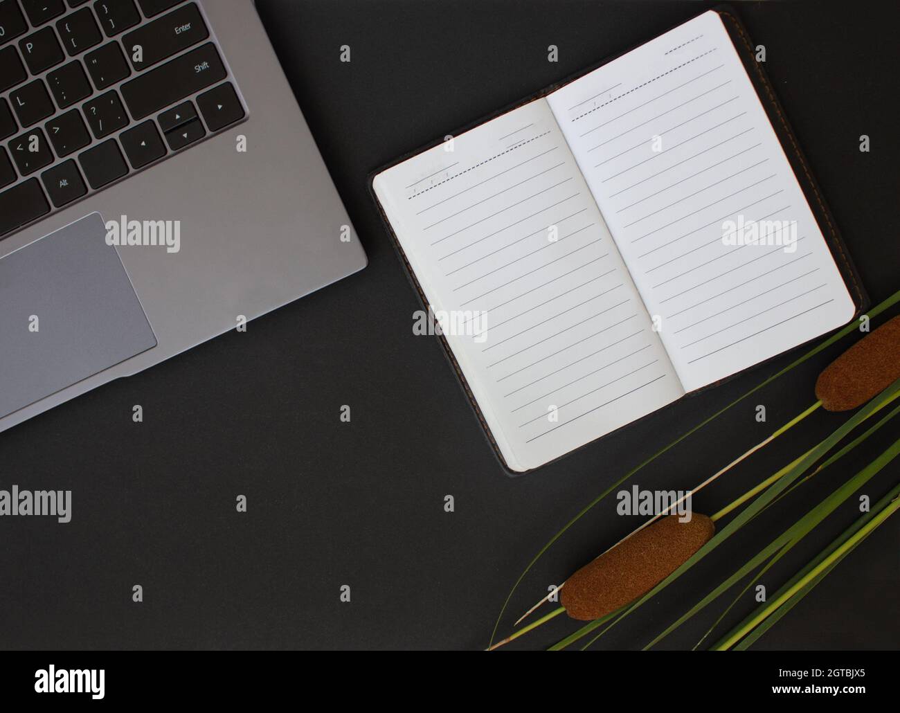 Scrivania da ufficio. Portatile, mobile su sfondo scuro. Spazio di lavoro elegante. Foto Stock