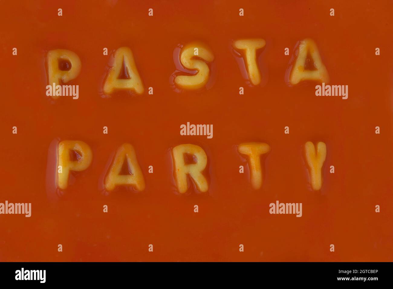 Lettere di pasta arancione Spelling le parole Pasta Party in salsa di  pomodoro rosso visto dall'alto Foto stock - Alamy