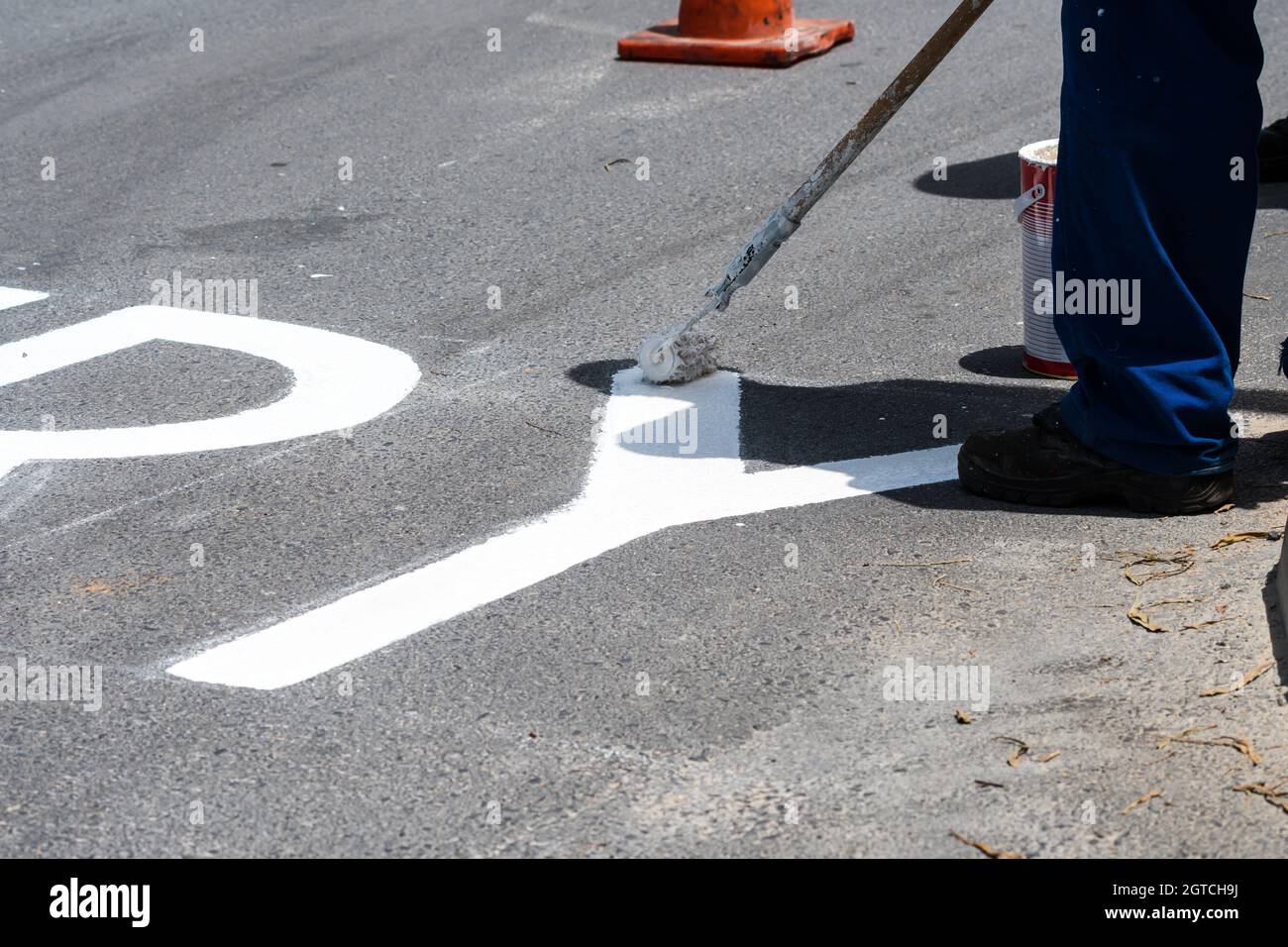 operatore che utilizza il rullo di vernice per dipingere strada bianca o segnaletica stradale su asfalto fondo stradale concetto di manutenzione stradale Foto Stock
