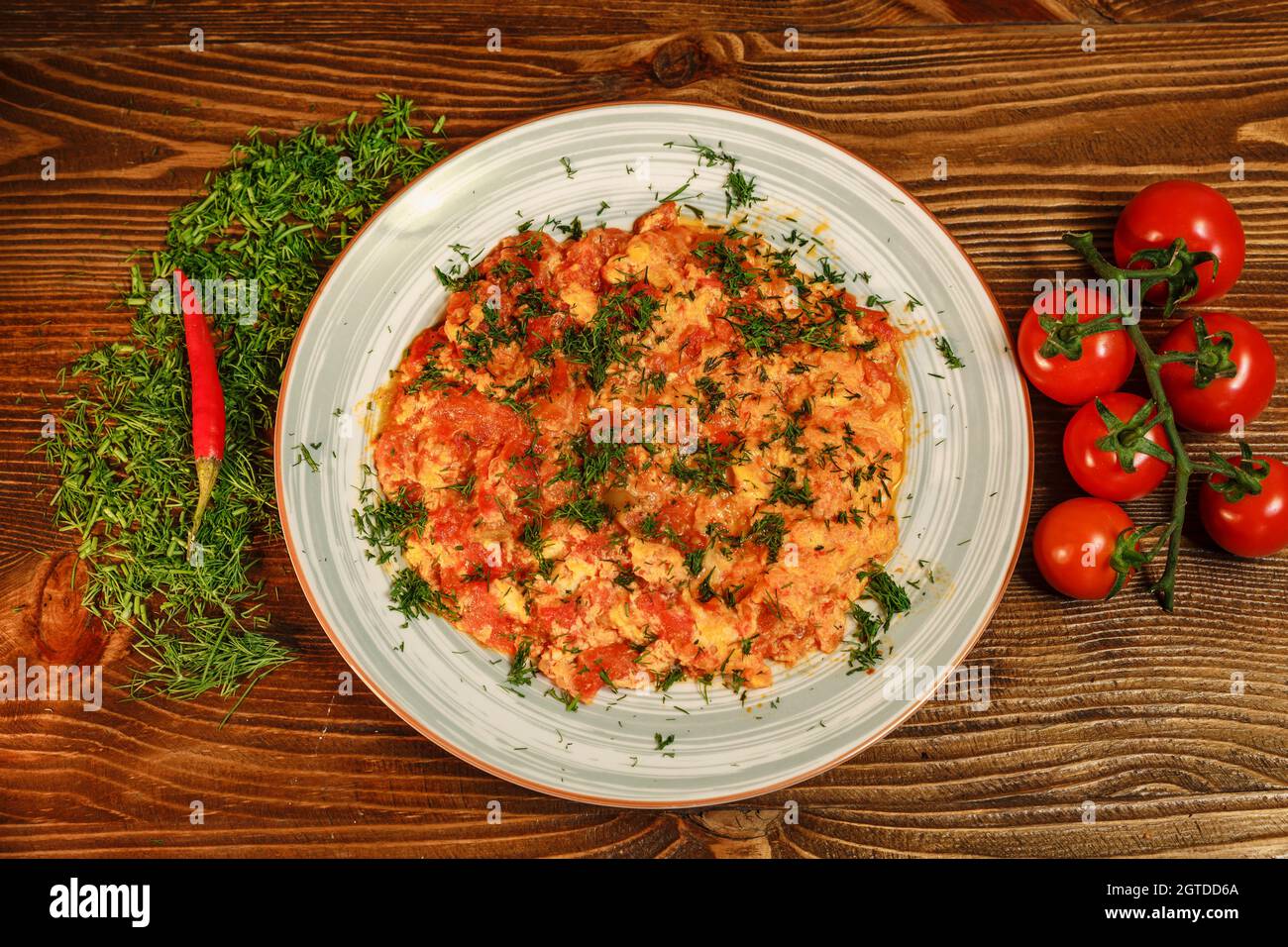 Uova e pomodori fritti serviti nel ristorante armeno decorato con peperoncino, verdure e pomodori ciliegini. Ingredienti molto gustosi Foto Stock