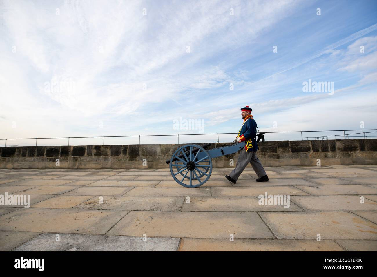 Konigstein, Germania. 2 ottobre 2021. 02 ottobre 2021, Sassonia, Königstein: Un uomo nell'uniforme dell'artiglieria reale britannica spinge un piccolo cannone al suo posto sulla Fortezza di Königstein. Per il "tuono di cannone sulla valle dell'Elba" diversi gunner hobby vogliono rivivere il tempo di quel tempo per un giorno con diverse repliche di cannoni in abiti storici. Foto: Daniel Schäfer/dpa-Zentralbild/Daniel Schäfer credito: dpa Picture Alliance/Alamy Live News Foto Stock
