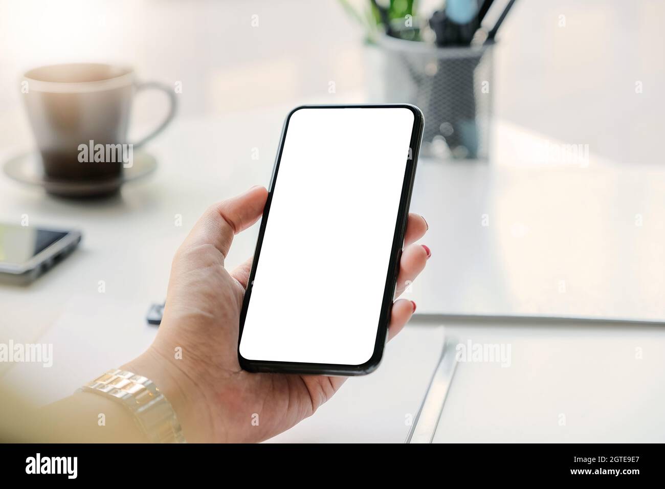 Smartphone da donna in mano sul luogo di lavoro. Telefono cellulare con  schermo vuoto per montaggio display grafico Foto stock - Alamy
